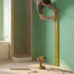 placo hydrofuge salle de bain hauteur - murs d'une salle de bain en rénovation habillés de plaques vertes hydrofuges, contrôle au niveau